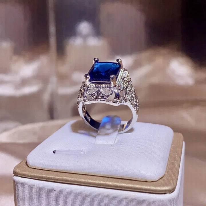 Silver ring with a blue gemstone on a display stand